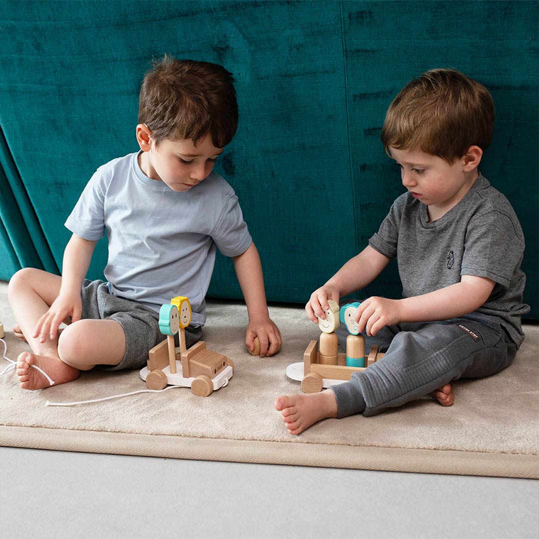 Wooden safari jeep toy with teal and cream animal-face blocks on play surface