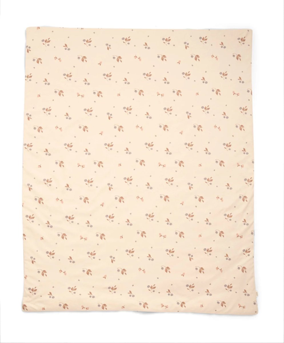 Quilt with cream base and small pink floral pattern, folded corner visible