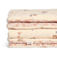 Folded quilt stack with cream and pink floral print, fabric label visible
