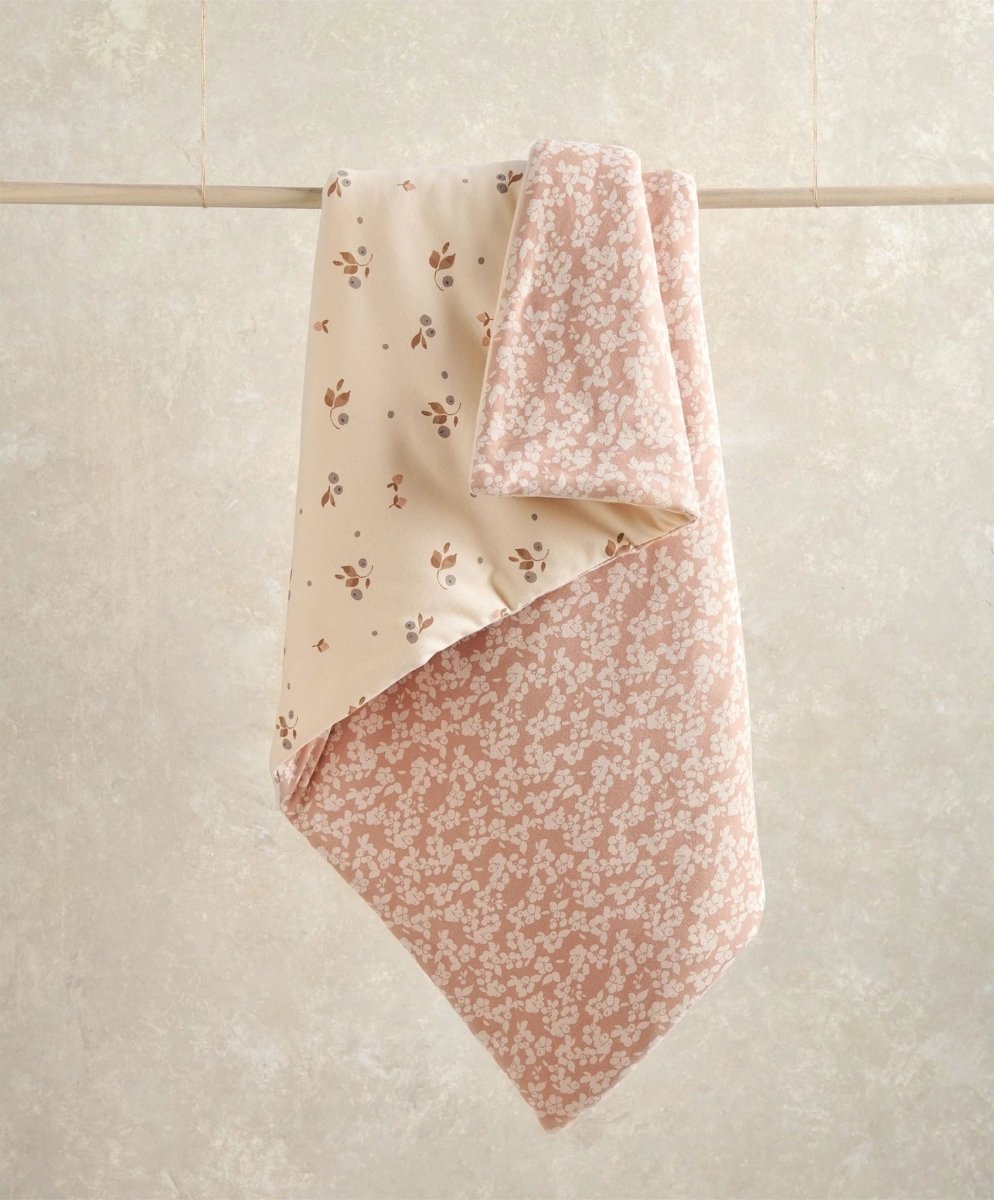 Floral quilt draped over hanger, cream side with small blossoms and pink reverse