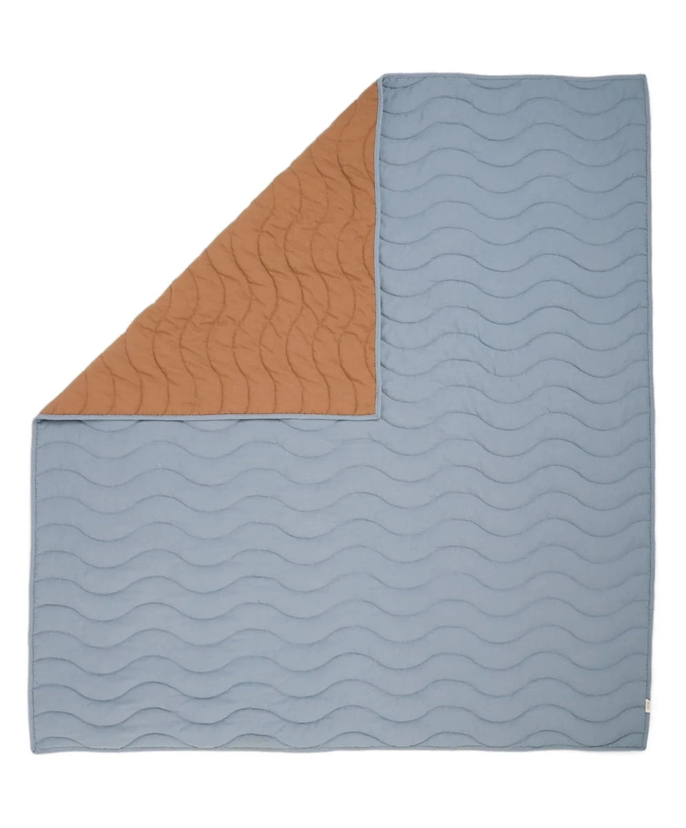 Wave quilt folded: light blue quilt top with wavy quilting and brown side panel