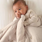 Soft taupe quilt with stitched motifs, draped over an infant