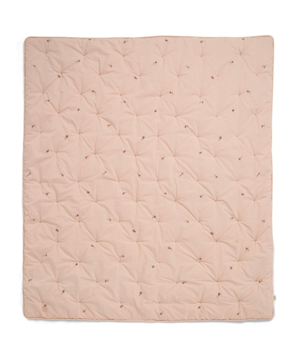 Light pink quilt blanket with quilted diamond pattern and scattered small floral motifs