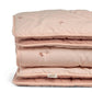 Folded light pink quilt with embroidered small floral details on quilted surface