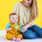 Barbell rattle toy with circular bead-filled ends, held near baby’s chest