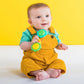 Barbell rattle toy with green and yellow end discs, baby holding the handle