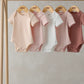 Hanging ribbed short-sleeve bodysuits, mix of white and blush pink shades, crew neck
