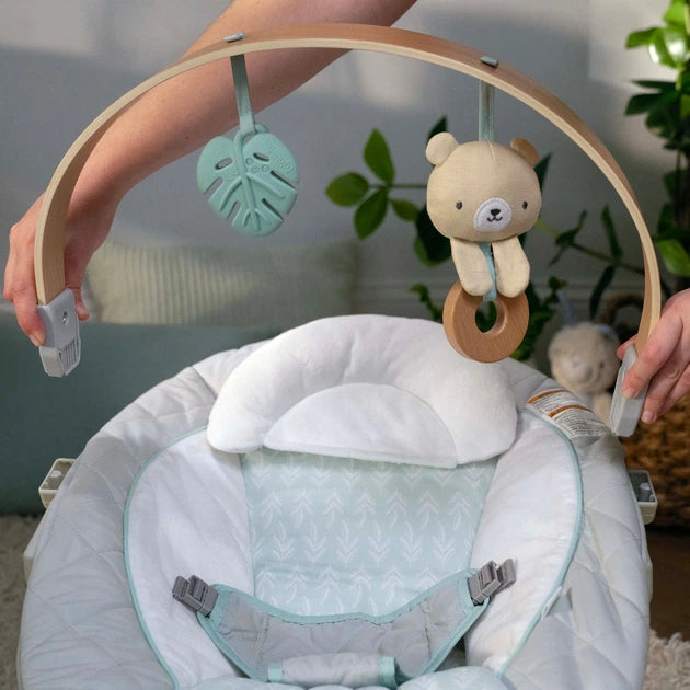 Portable baby swing with white-and-mint seat pad and hanging plush bunny toy