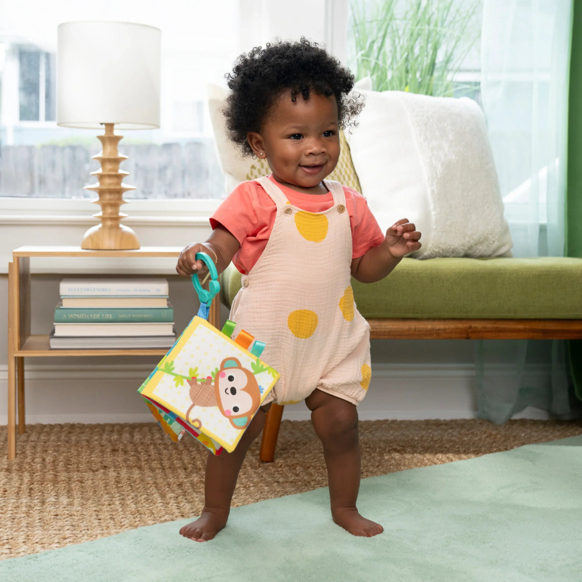 Soft cloth baby book with safari animal pages and handle rings, held upright