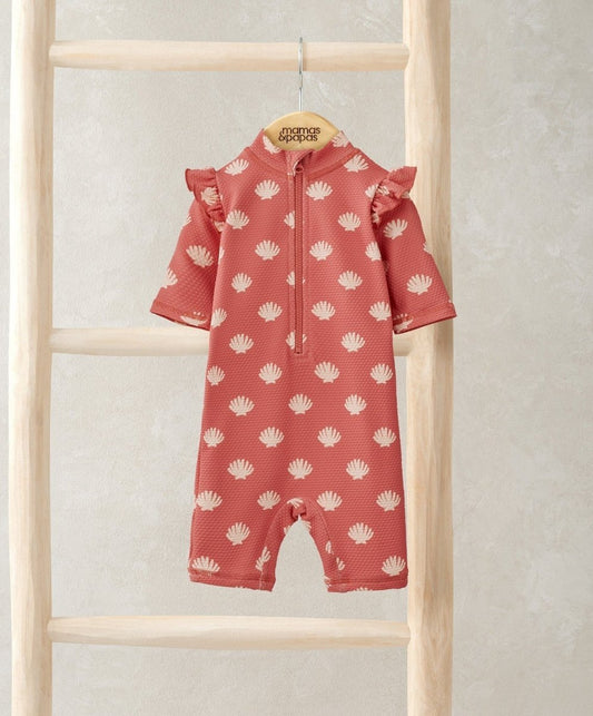 Coral pink rashsuit with all-over white shell pattern, zip front and ruffle sleeves.