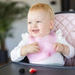 Ultrathin silicone bib, light pink, on a seated baby