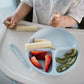 Light blue silicone suction plate with three sections in a high chair