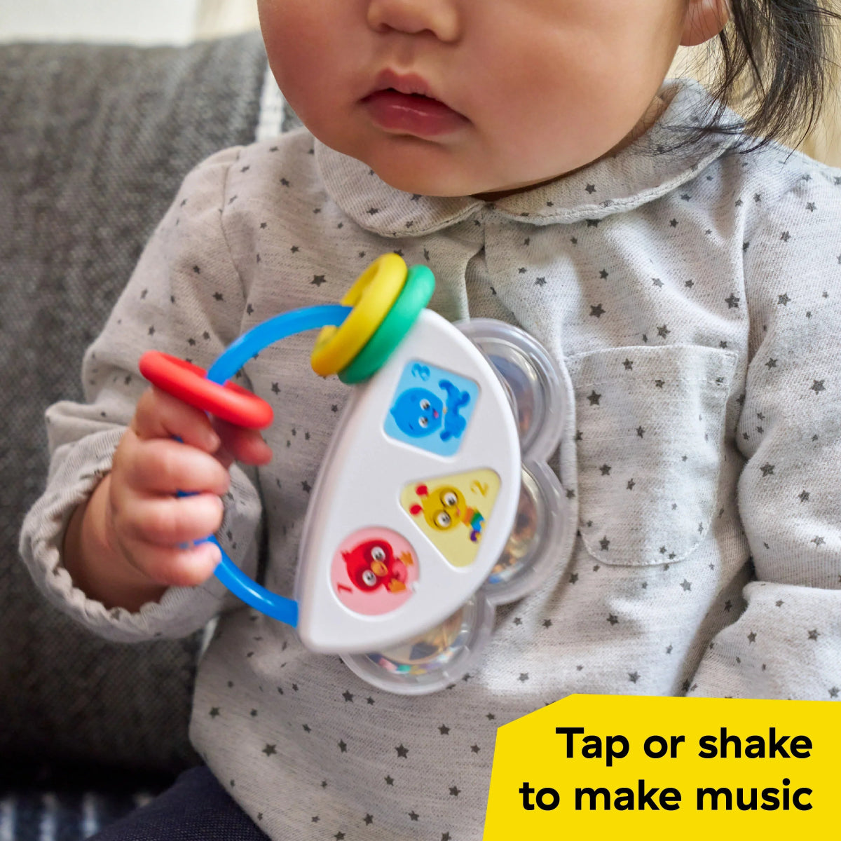 Baby holding a colorful 3-piece musical toy with chime buttons