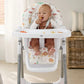 Baby high chair with white tray and animal-print cushion holding a seated baby
