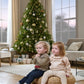Light beige snowflake knit jumper with ruffled high neck on seated child at Christmas tree