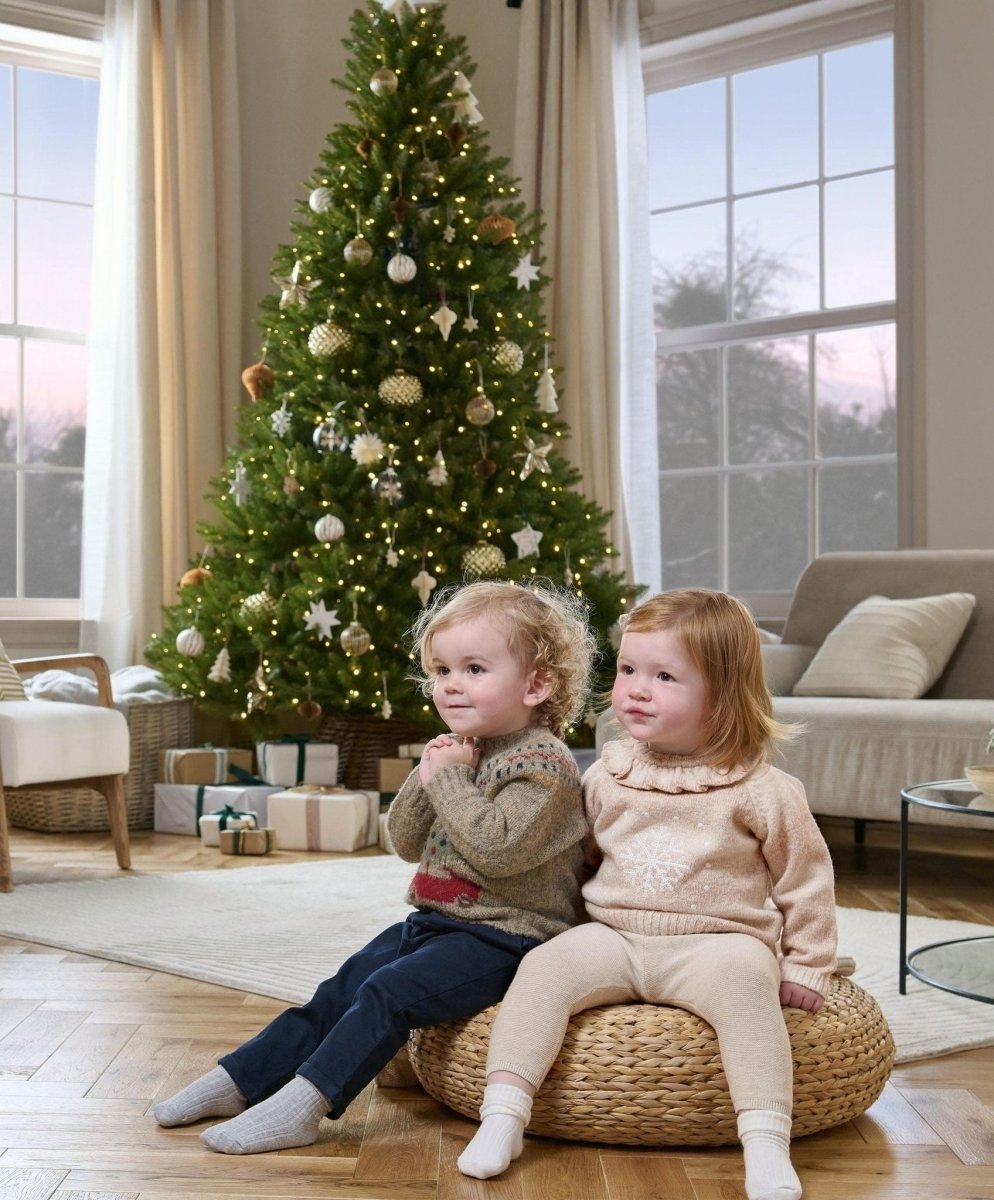 Light beige snowflake knit jumper with ruffled high neck on seated child at Christmas tree