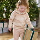 Light beige snowflake knit jumper with ruffled high neck on standing child
