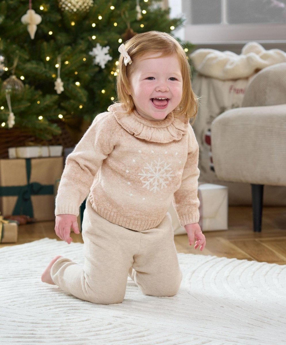 Light beige snowflake knit jumper with ruffled high neck on smiling child