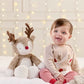 Plush reindeer soft toy with red nose and brown antlers beside a baby on a bed