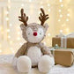 Plush reindeer soft toy with red nose and brown antlers, seated on a couch