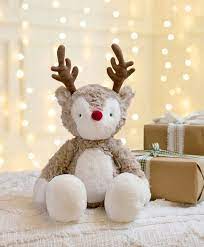 Plush reindeer soft toy with red nose and brown antlers, seated on a couch