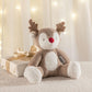 Plush reindeer soft toy with red nose and brown antlers, lying on a blanket