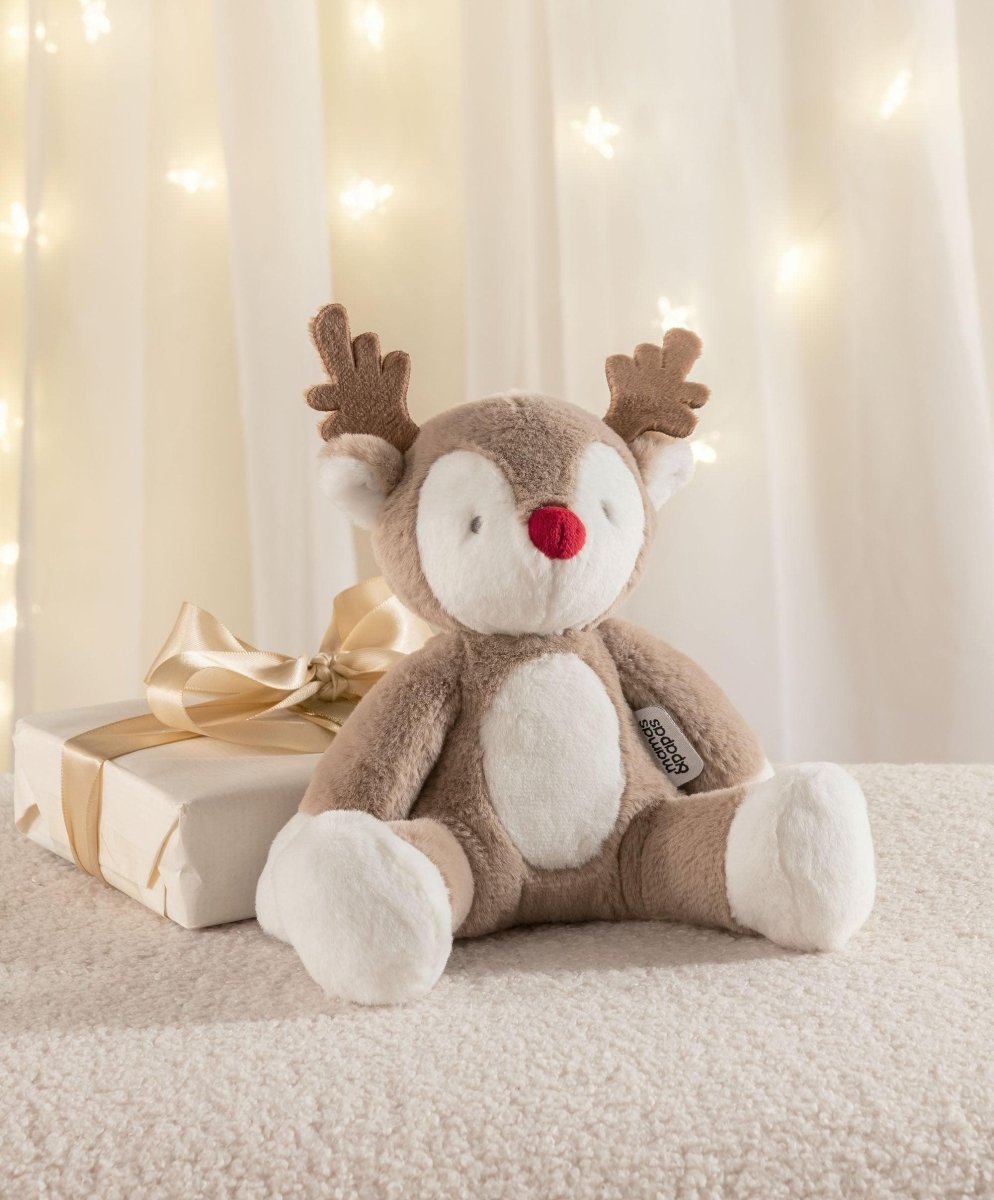 Plush reindeer soft toy with red nose and brown antlers, lying on a blanket