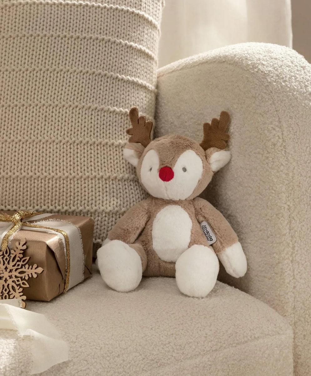 Plush reindeer soft toy with brown antlers and white belly, sitting on a chair