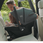 ISOFIX car seat installed in car, gray seat with canopy and harness