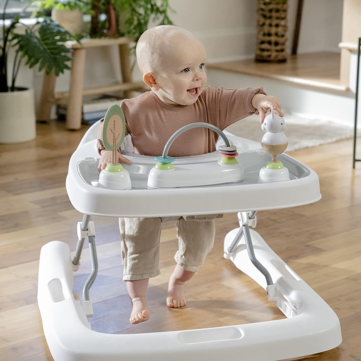 White baby activity walker with gray seat pad and dangling activity toys