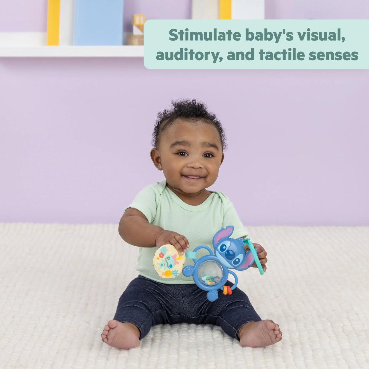 Baby holding blue Stitch tummy tumble activity toy with circular mirror and dangling parts