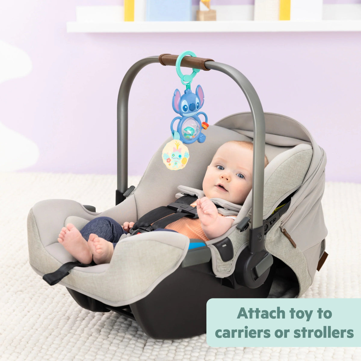 Stitch tummy tumble activity toy attached to gray baby carrier, teal handle and mirror