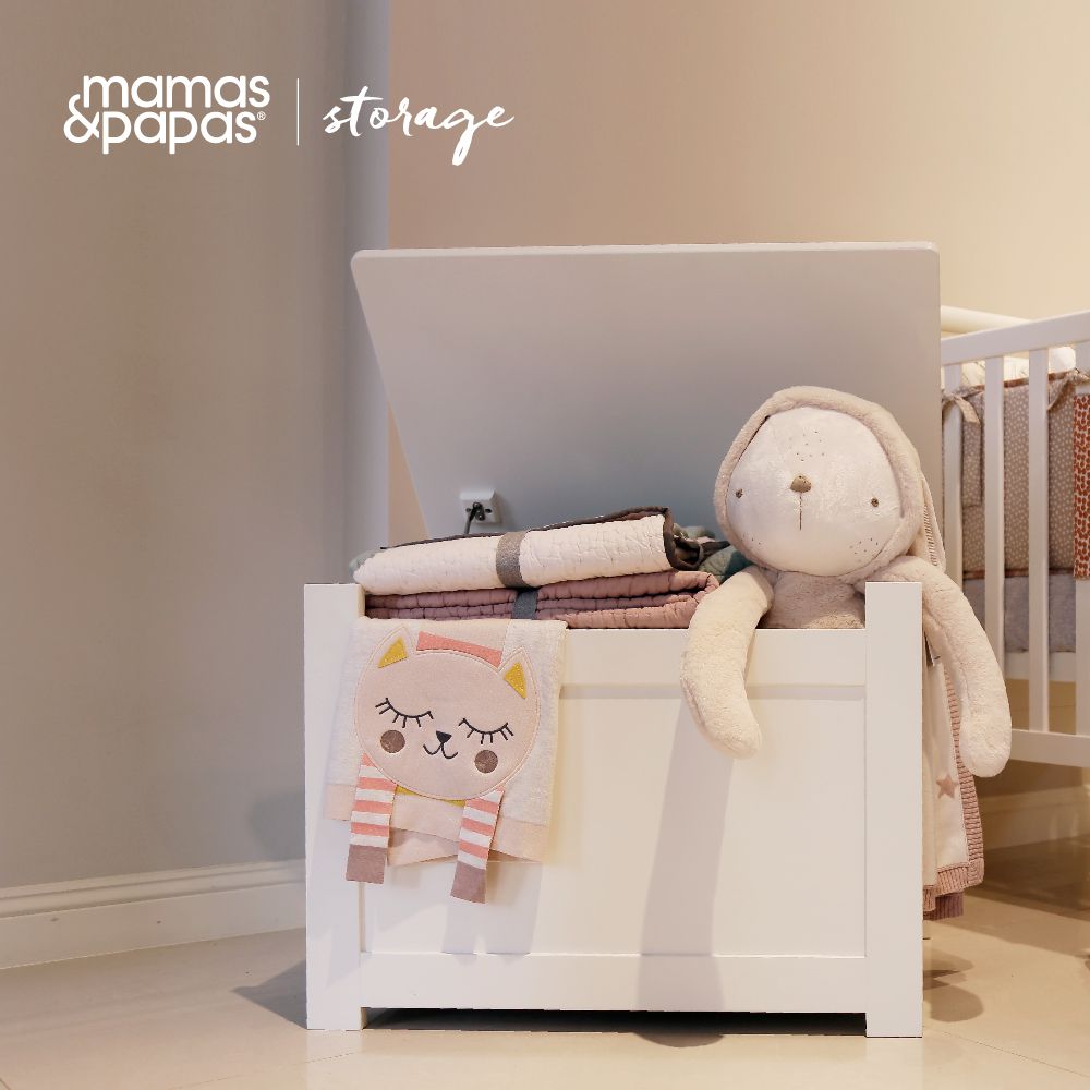 Ivory storage box with lift-top lid, open with folded blankets and a plush toy