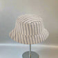 Blue-and-white striped chambray bucket hat with panel stitching and downward brim.