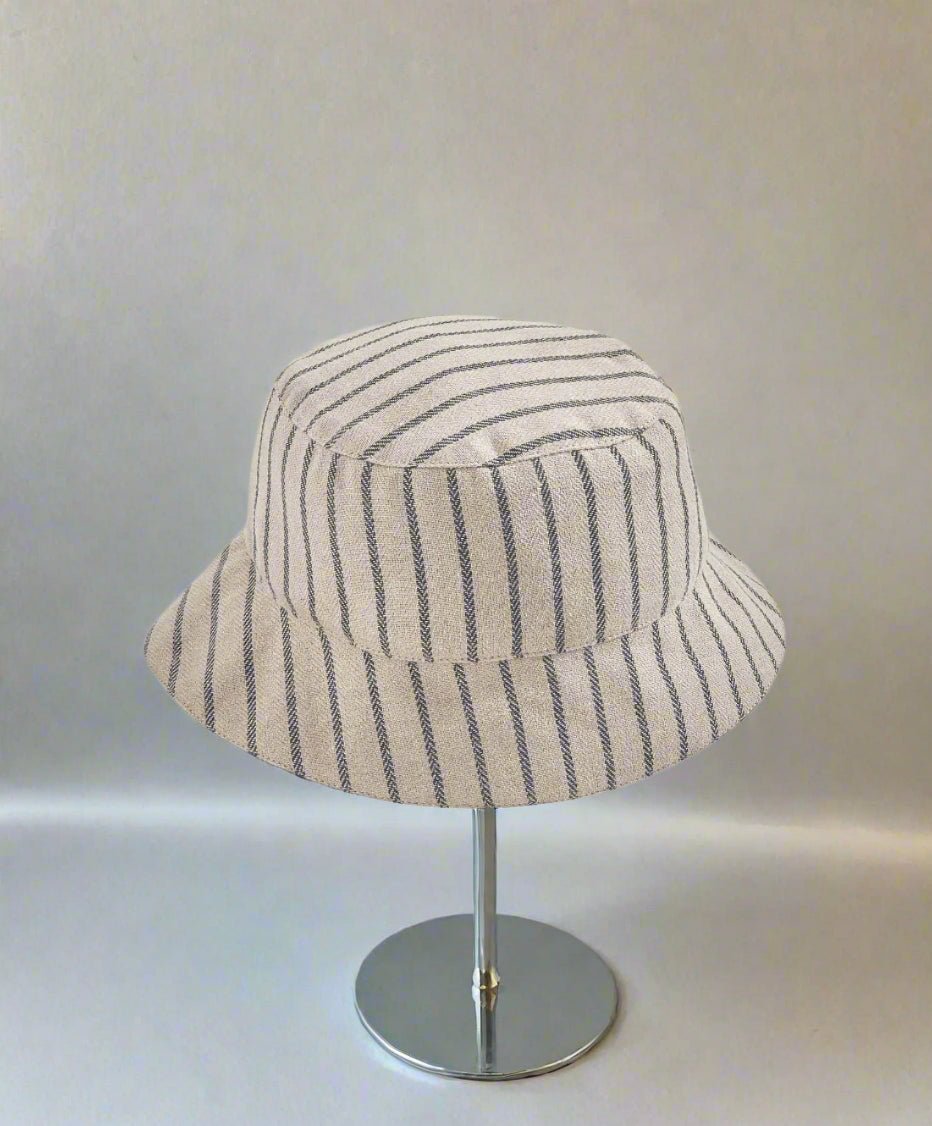 Chambray bucket hat in blue-and-white stripes with stitched crown and wide brim.