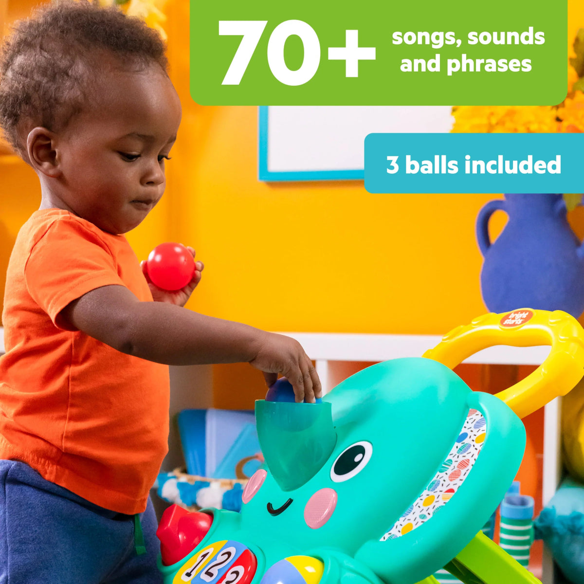 Child reaching a red ball toward turquoise elephant walker with face and buttons