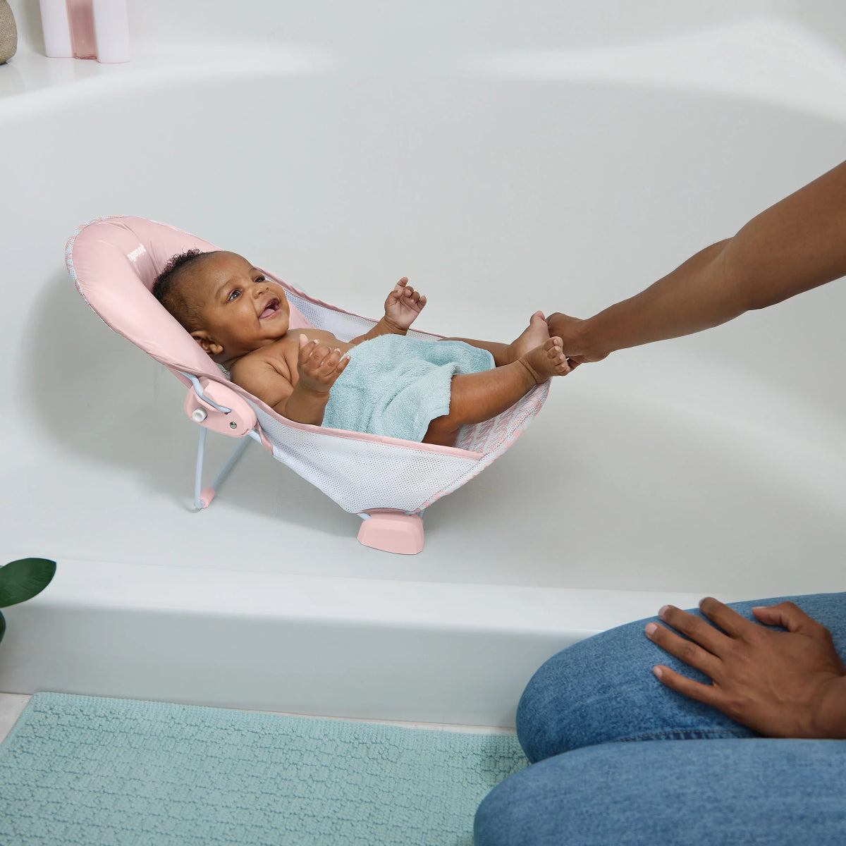 Two-position foldaway baby bather, pink headrest and light blue padded hammock