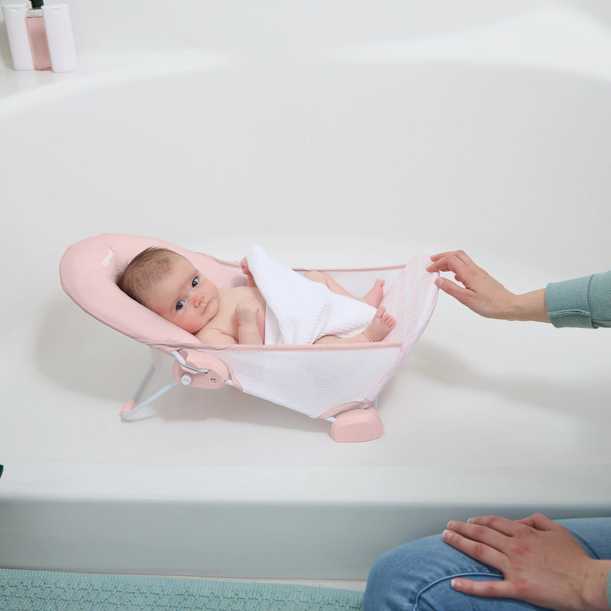 Foldaway baby bather with pink frame and white inner sling, two-position design