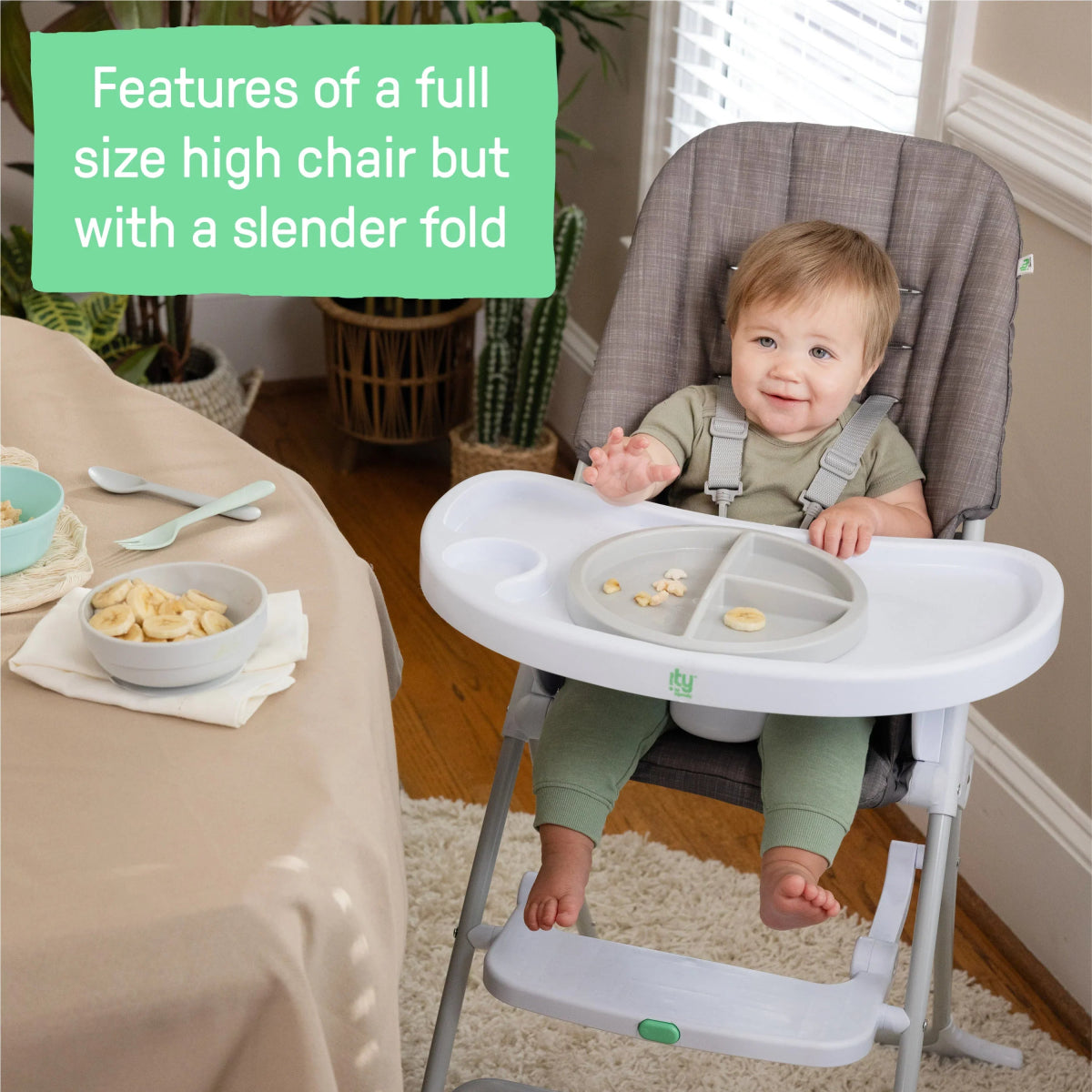Gray high chair with white tray and toddler seated in padded seat.