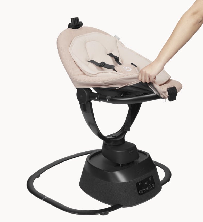 Beige baby bouncer seat reclined on black base, safety harness and legs