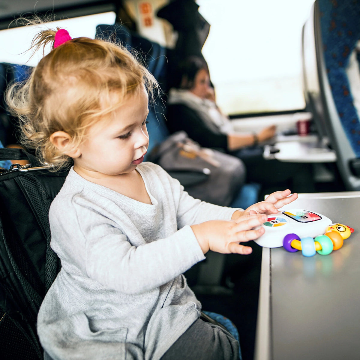 Baby playing with handheld musical toy featuring colorful icon panel and character