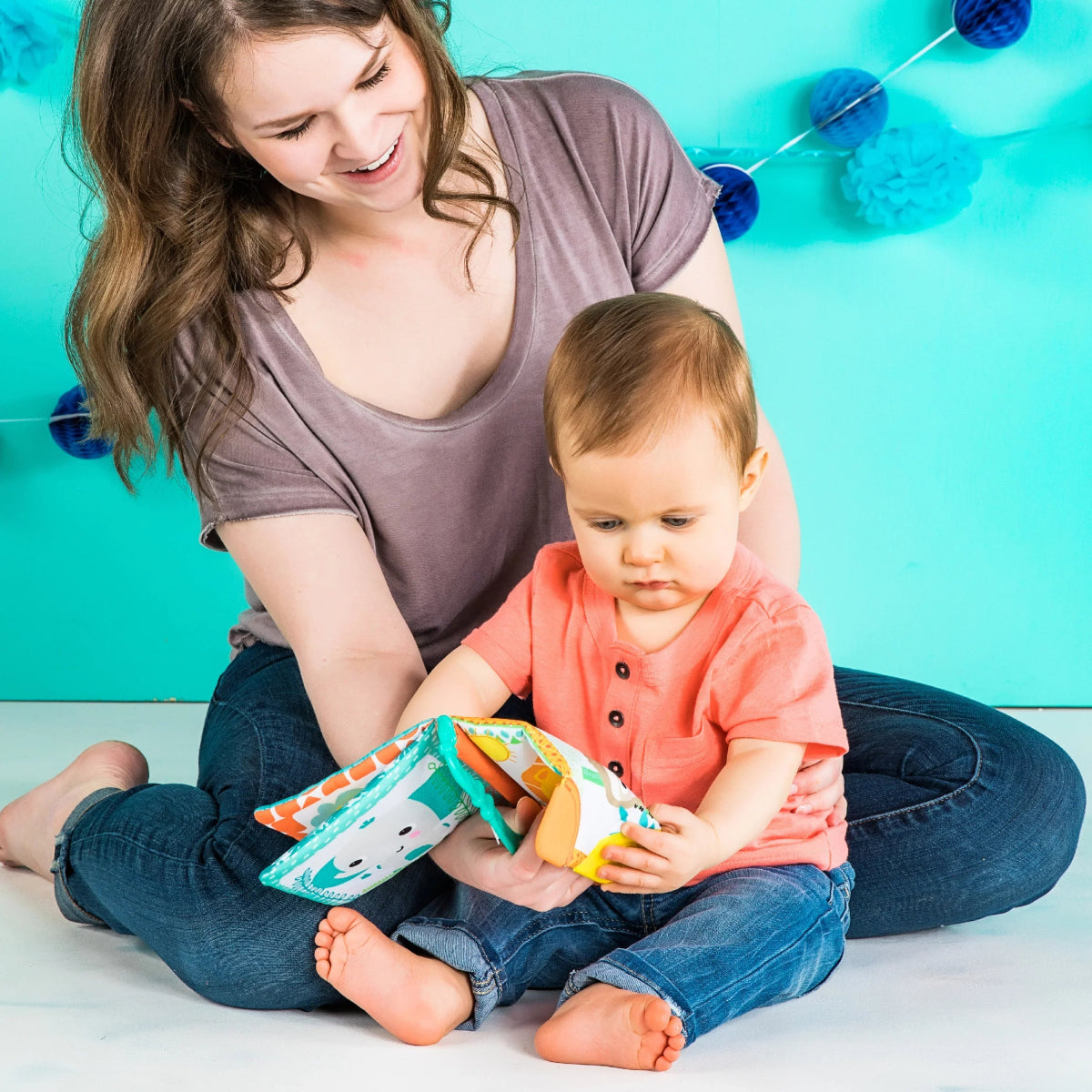 Toddler holding a colorful soft fabric book toy with animal pages