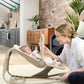 Baby rocker and bouncer with magnetic toy bar, light tan seat, baby reclined