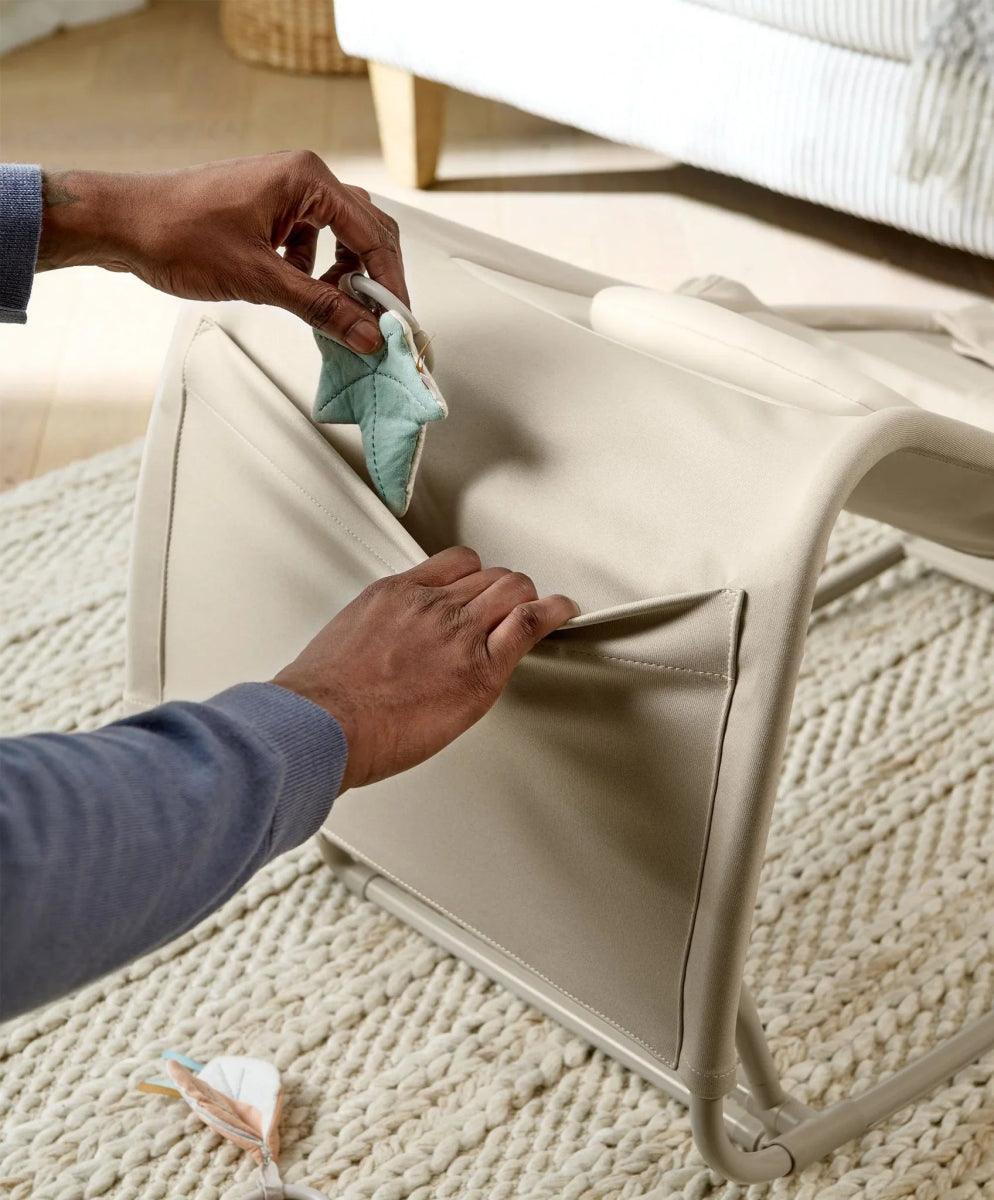 Baby rocker and bouncer fabric side panel being opened, light beige seat