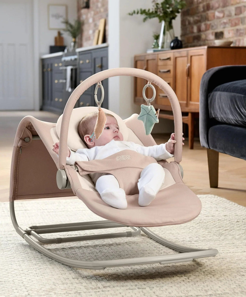 Baby rocker and bouncer with toy bar rings, tan seat, baby lying back