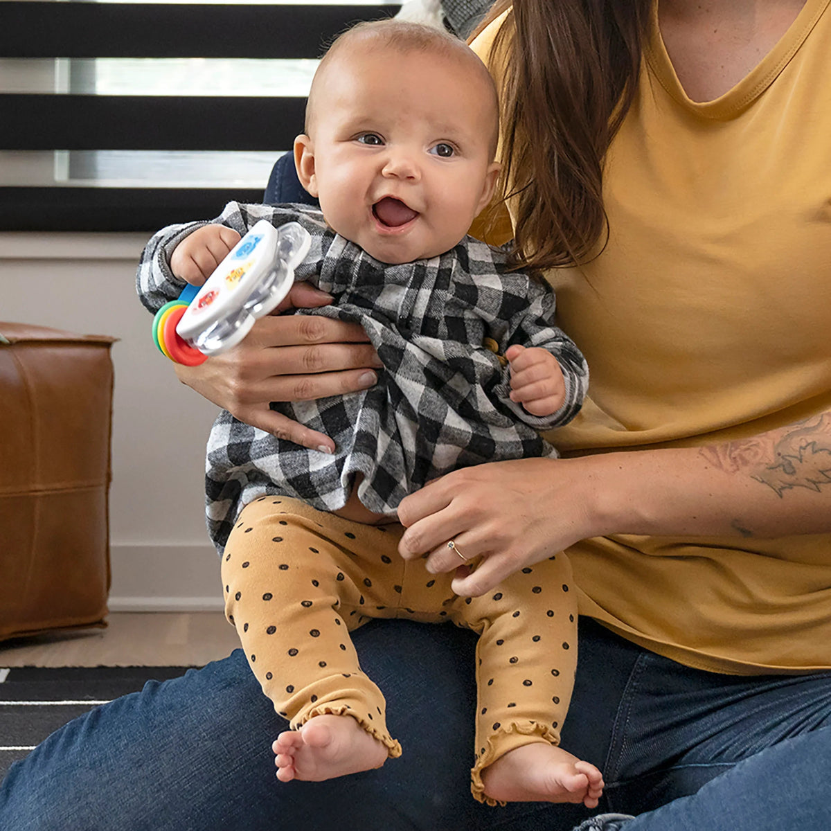Baby with tambourine rattle, silver jingles and colorful rings, held by a caregiver