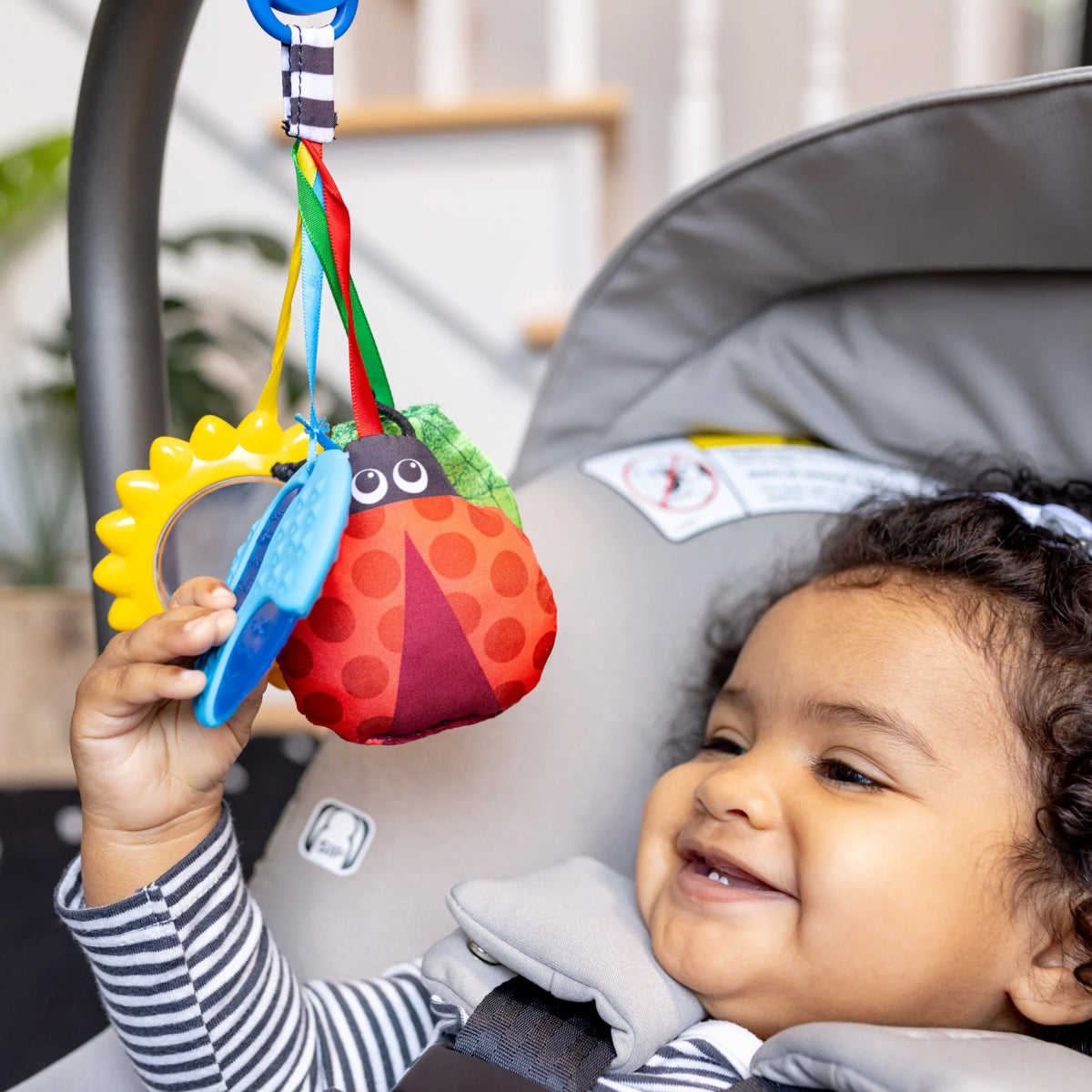 Baby playing with hanging sensory toy: sun and animal fabric pieces