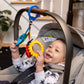 Sensory toy hanging from stroller handle with colorful fabric shapes