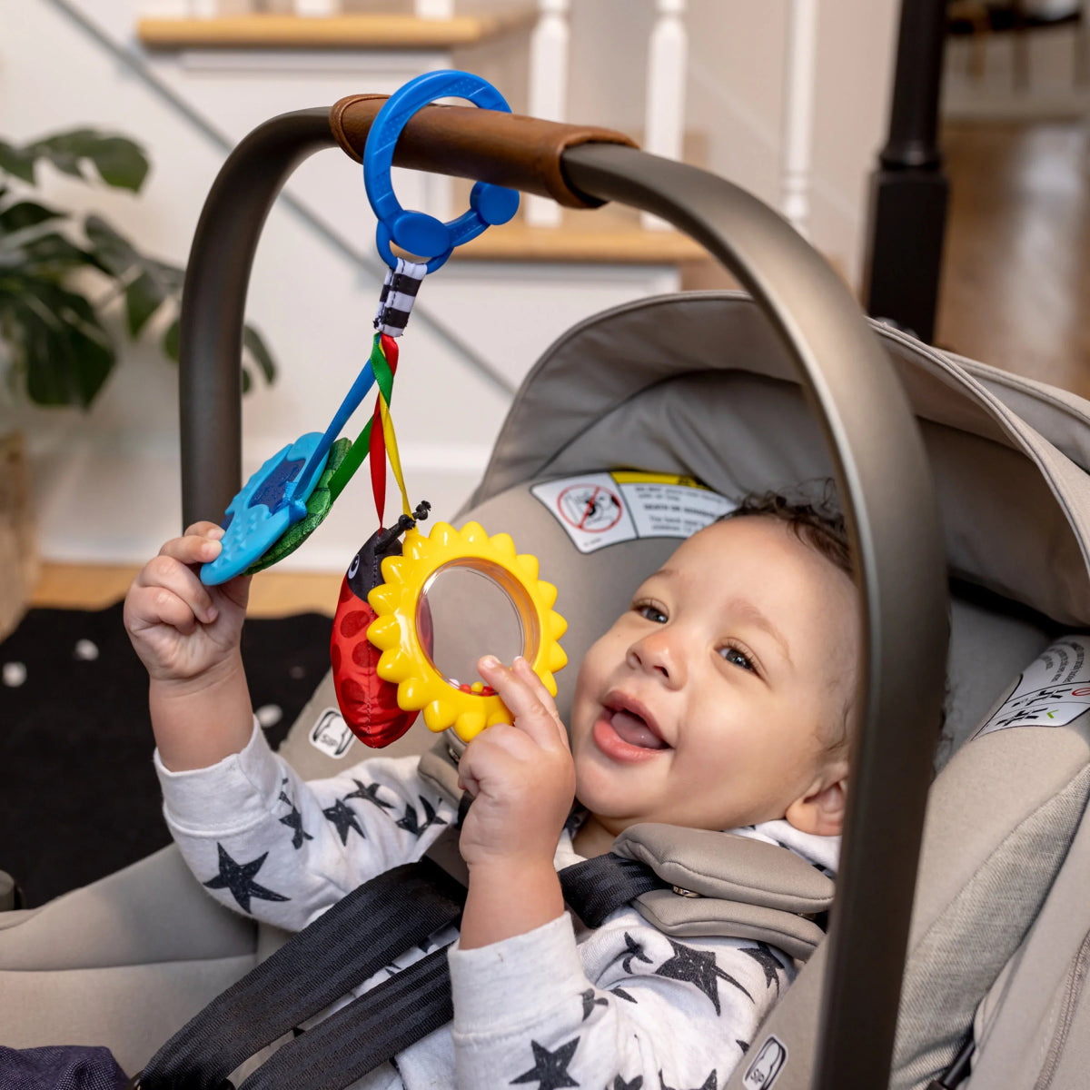 Sensory toy hanging from stroller handle with colorful fabric shapes