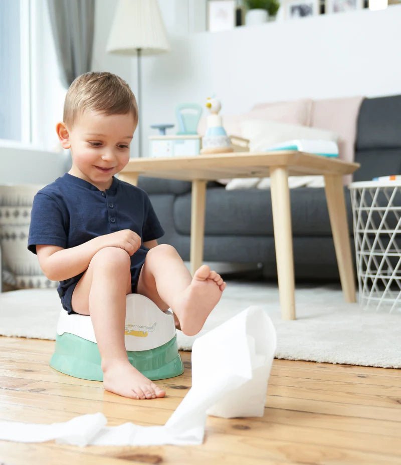 Children’s training potty with removable bowl in green and white, child kneeling beside it